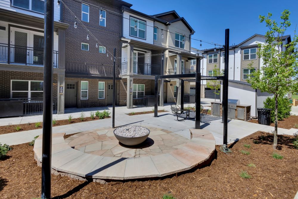 Outdoor firepit and hanging lights with townhomes in the background